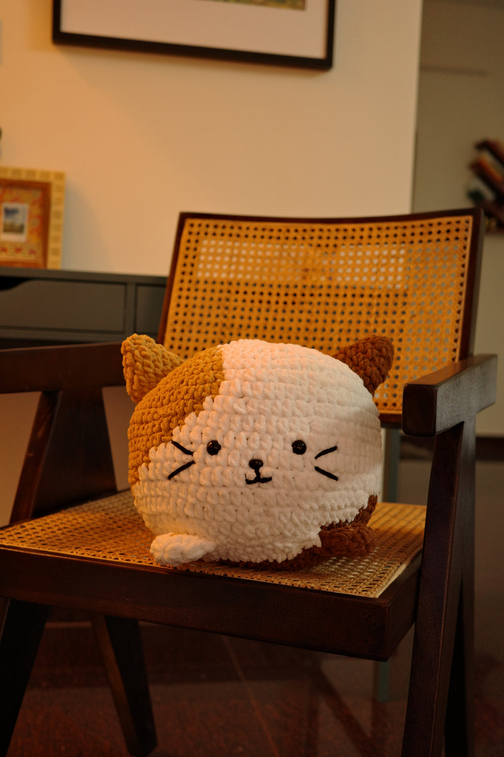 Crocheted cat cushion decoration on a wooden shelf with a blurred background