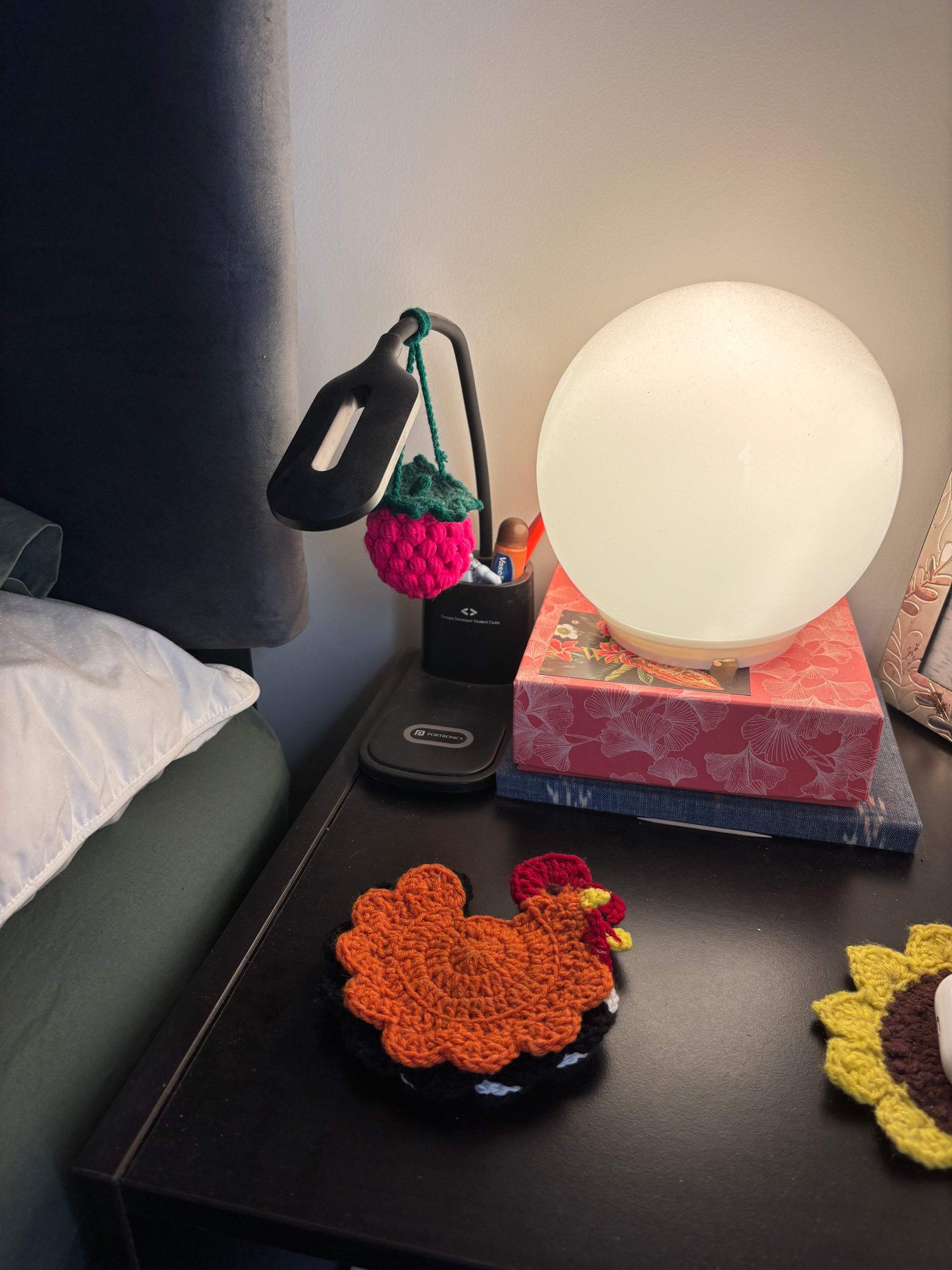 Nightstand with a lamp, phone, and decorative items including a crochet chicken.