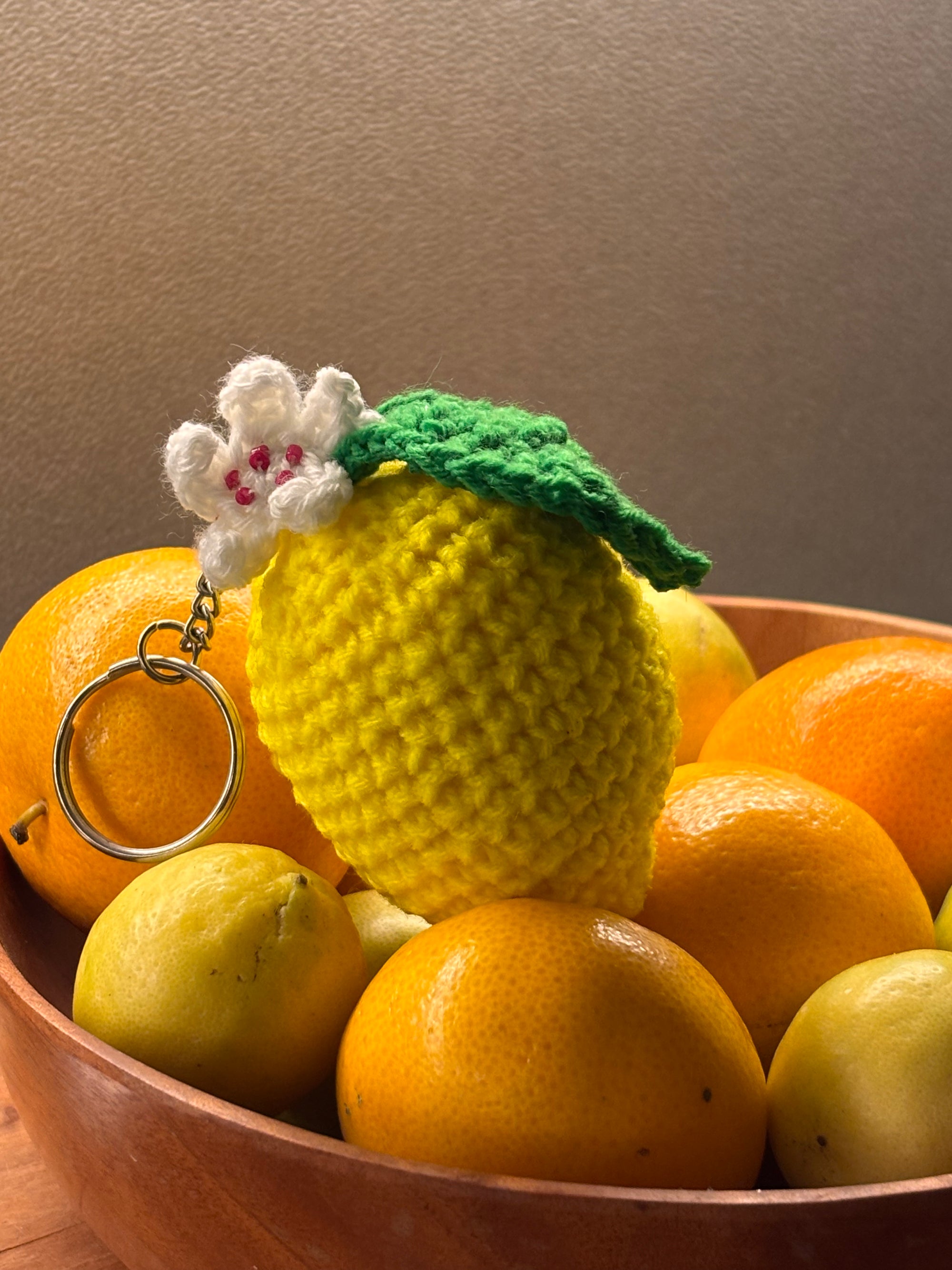 yellow crochet lemon keychain with a white flower and a green leaf