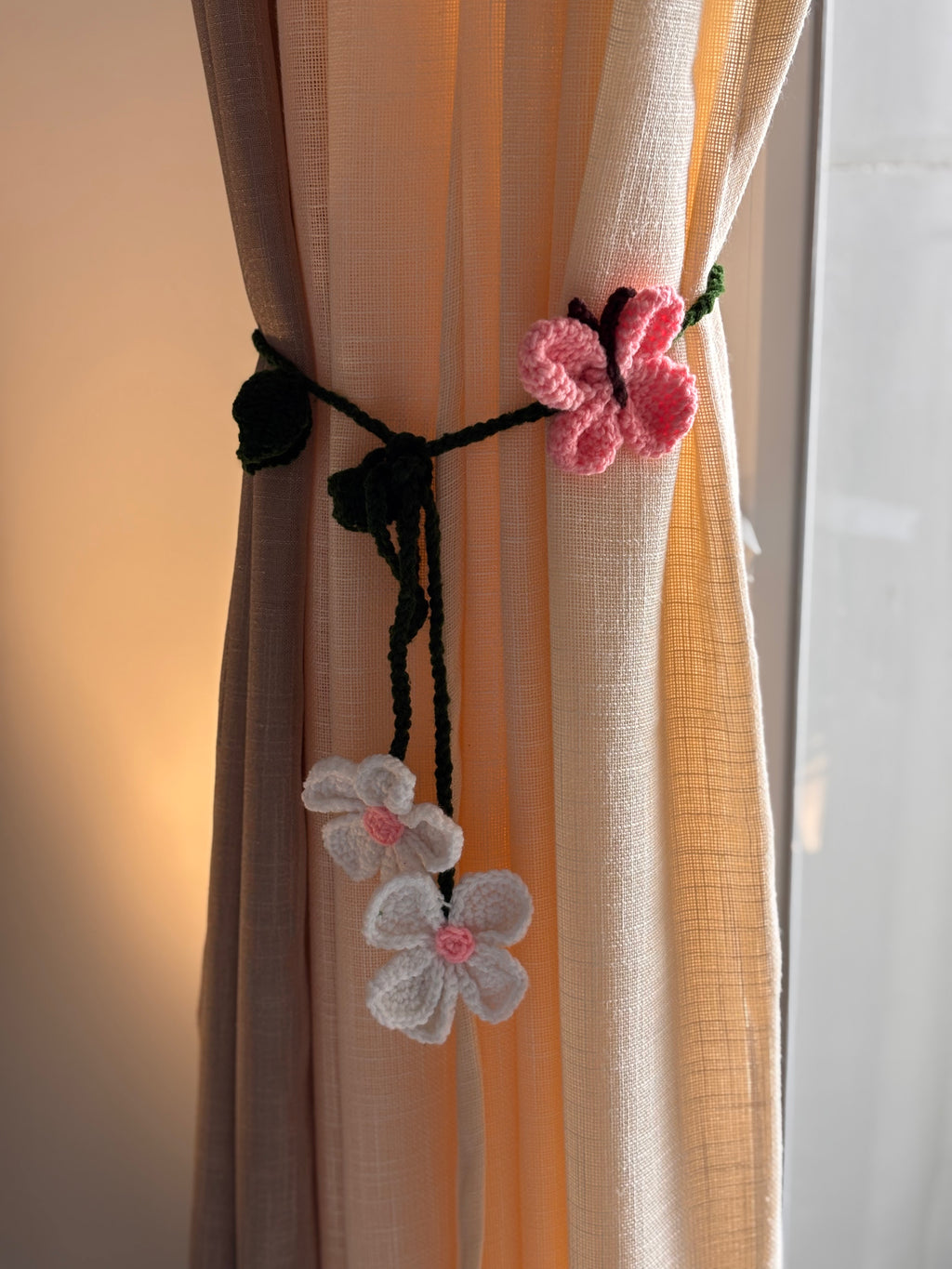 Decorative curtain tiebacks with floral designs on a curtain.