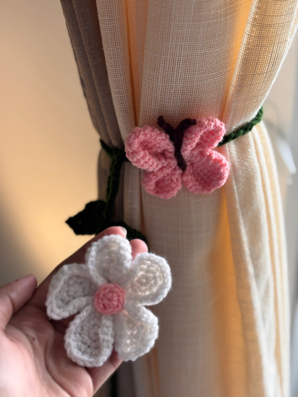Handmade crochet butterfly and flower curtain tiebacks against a curtain background