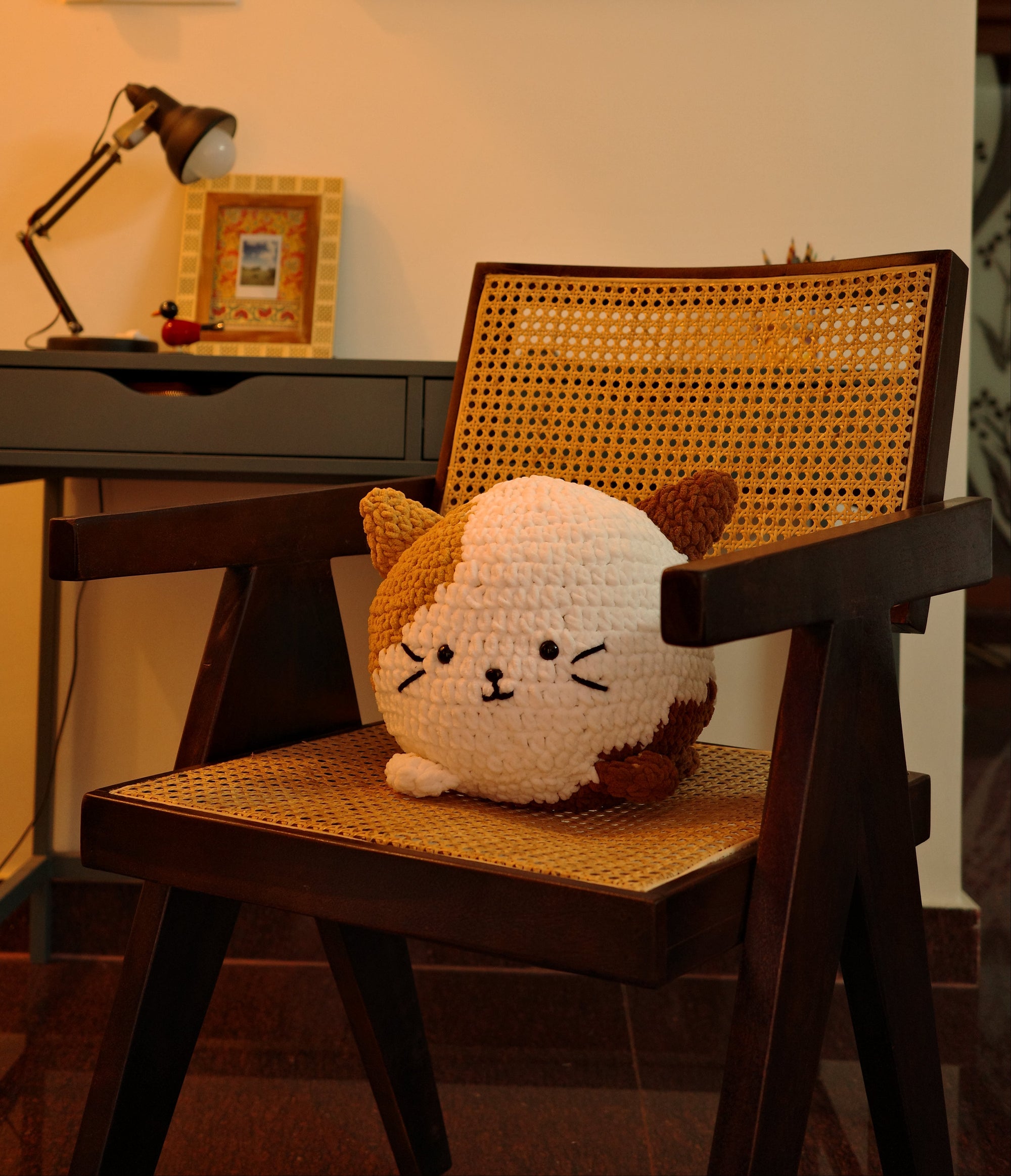 Stuffed animal toy on a chair with a colorful painting on the wall.