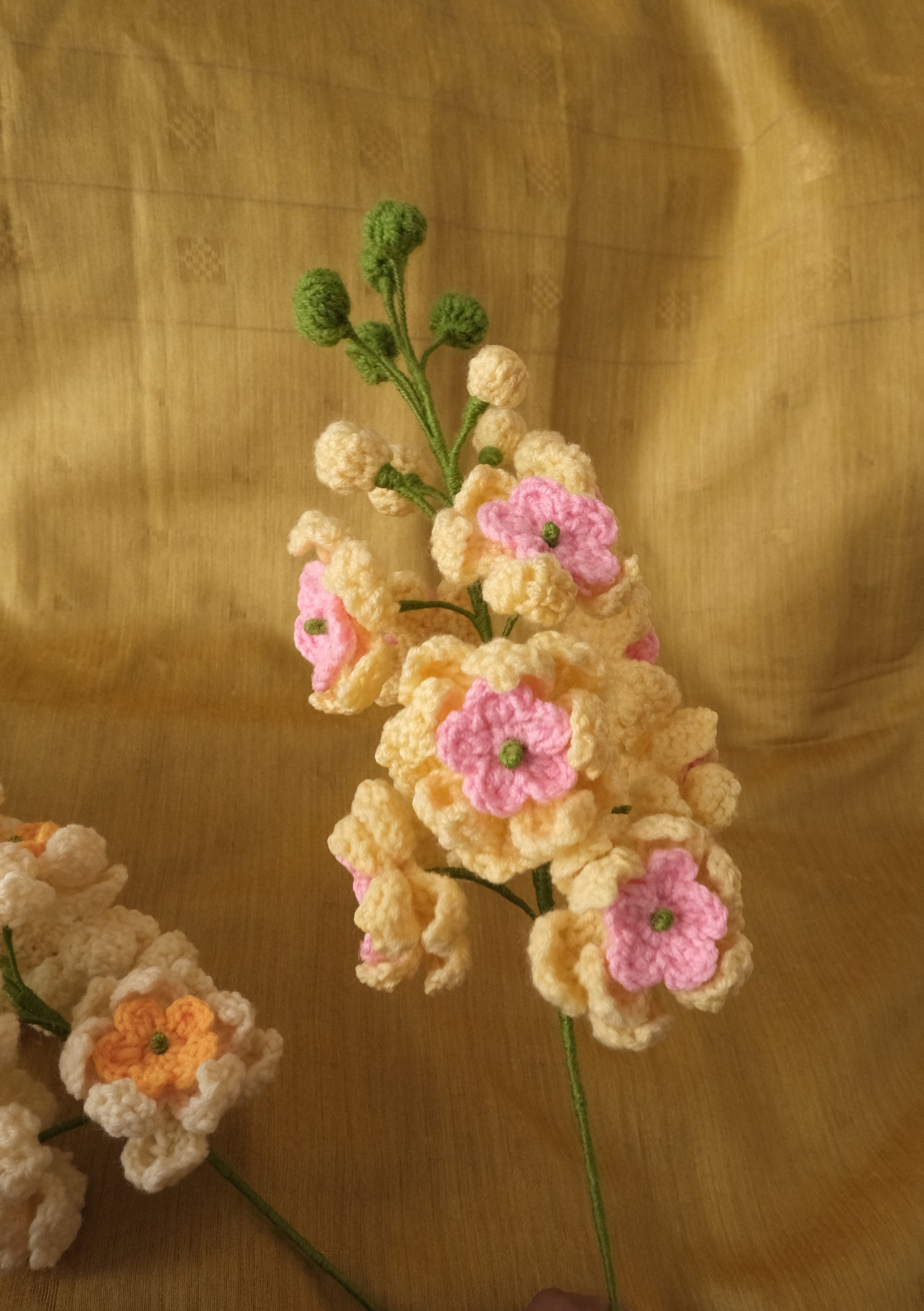 Handmade crocheted artificial flowers in cream, yellow, orange, and pink.