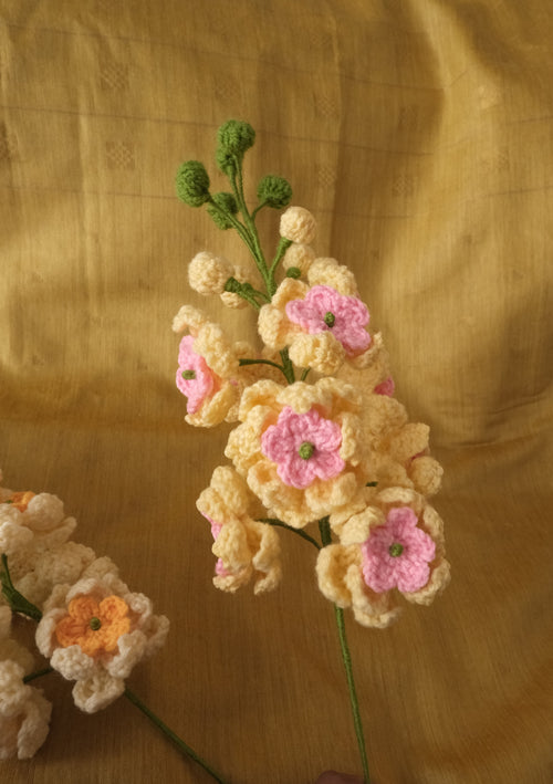 Handmade crocheted artificial flowers in cream, yellow, orange, and pink.