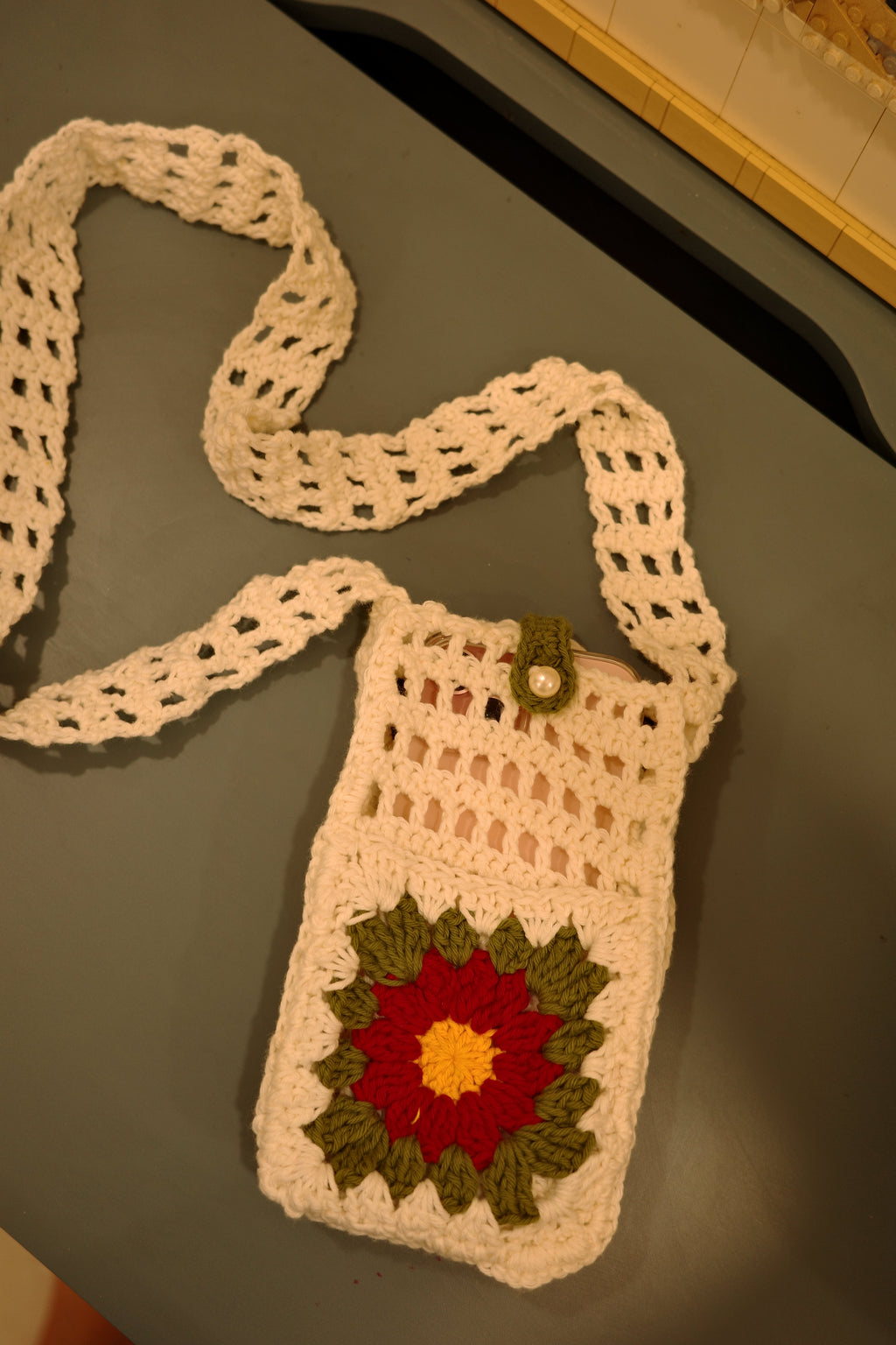 white handmade crochet phone holder with flap and red flower detail