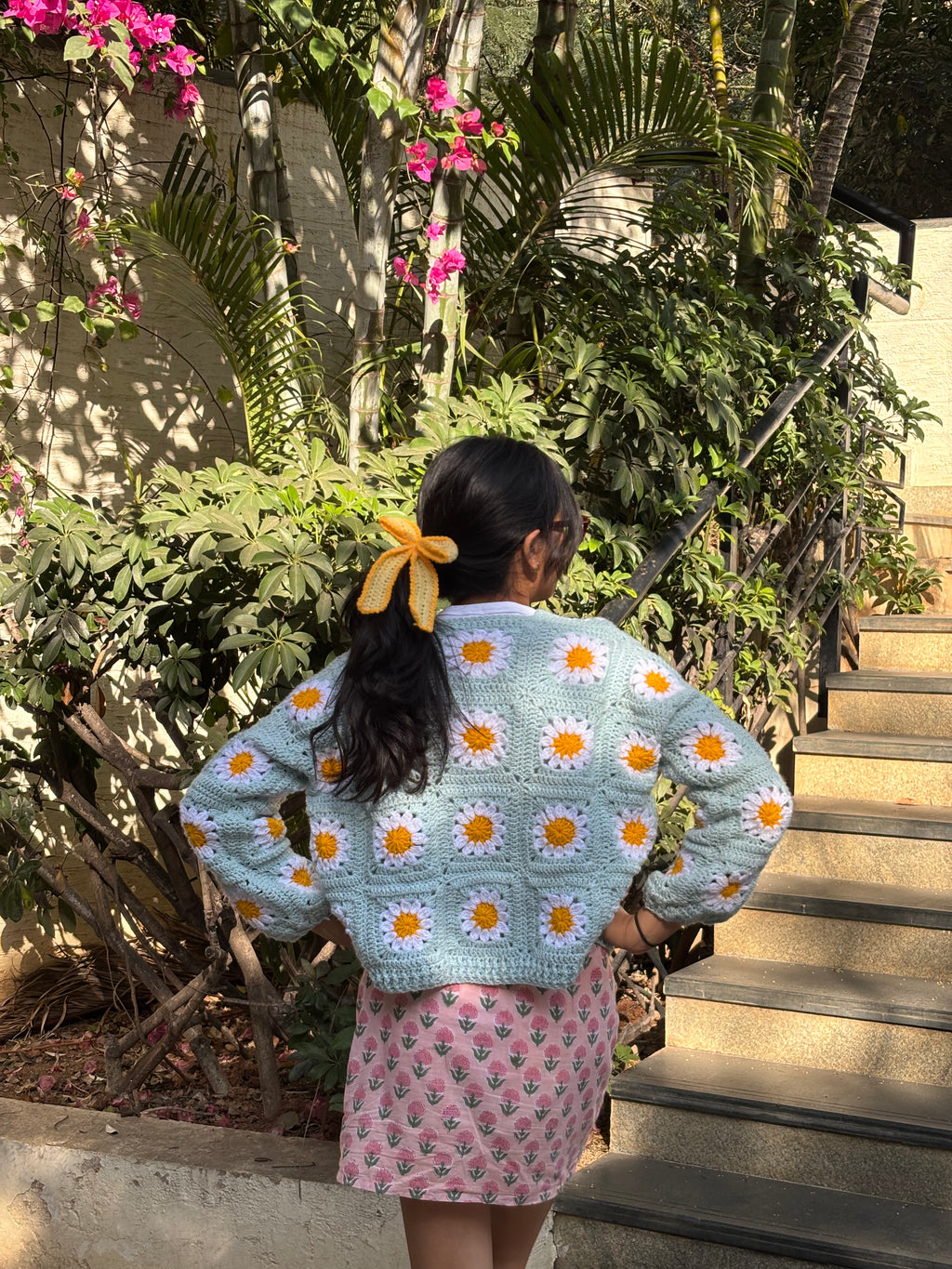 handmade crochet daisy cardigan with granny square floral pattern, cozy oversized knitwear in soft pastel tones of blue, white, and yellow