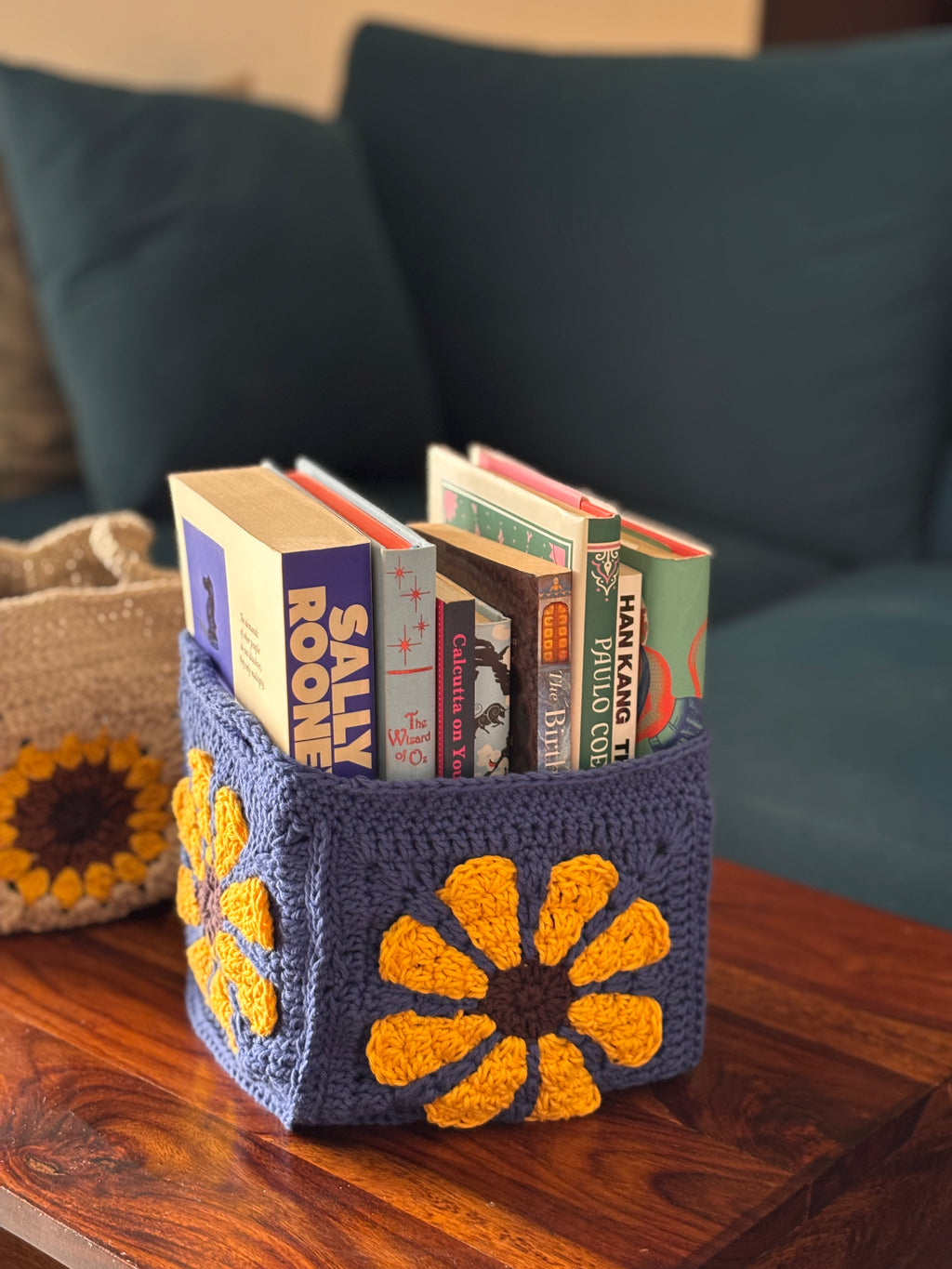 handmade crochet floral basket with yellow flower pattern on navy base holding books