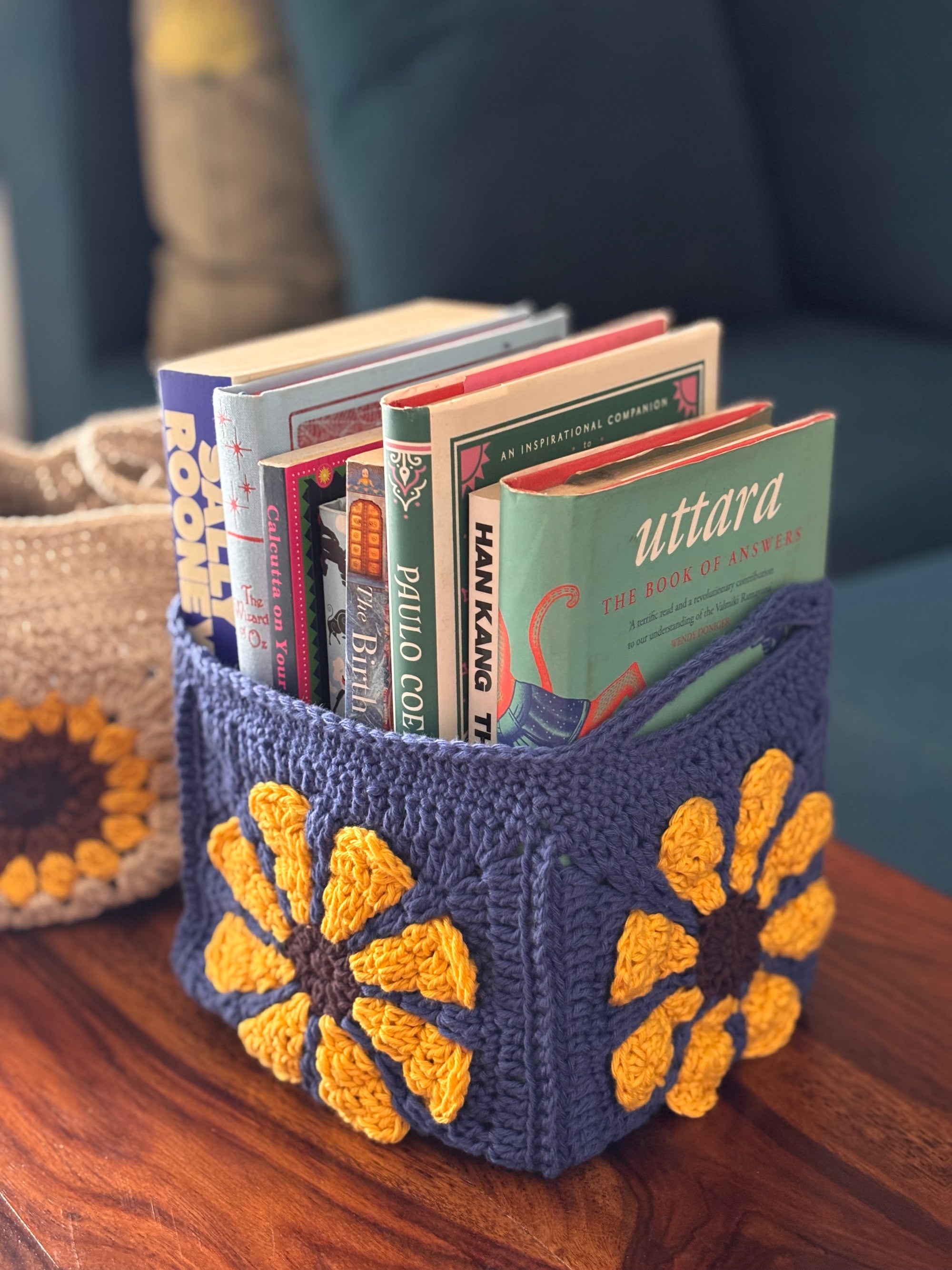 Crocheted basket with books inside on a wooden surface