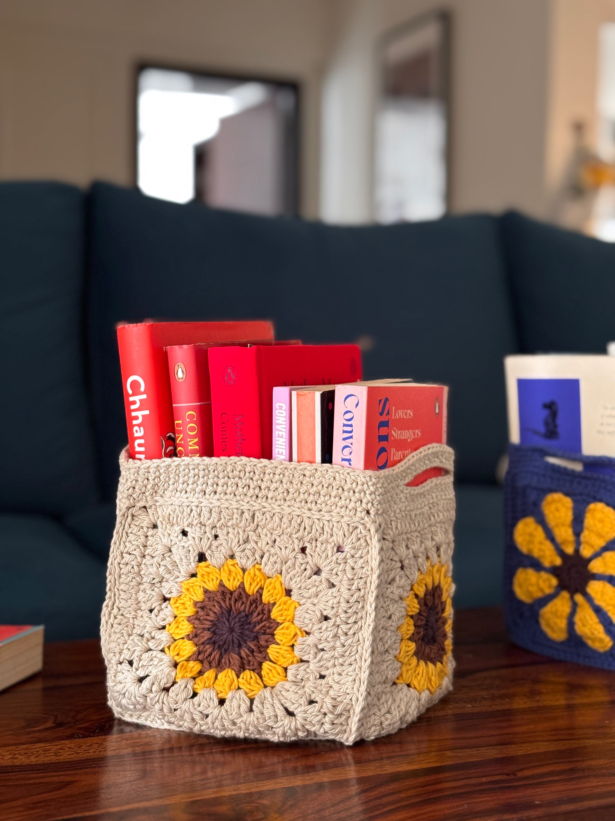 handmade crochet granny square basket with sunflower design holding books