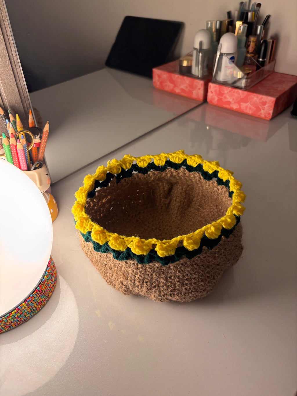 Knitted basket with yellow flower decorations on a desk