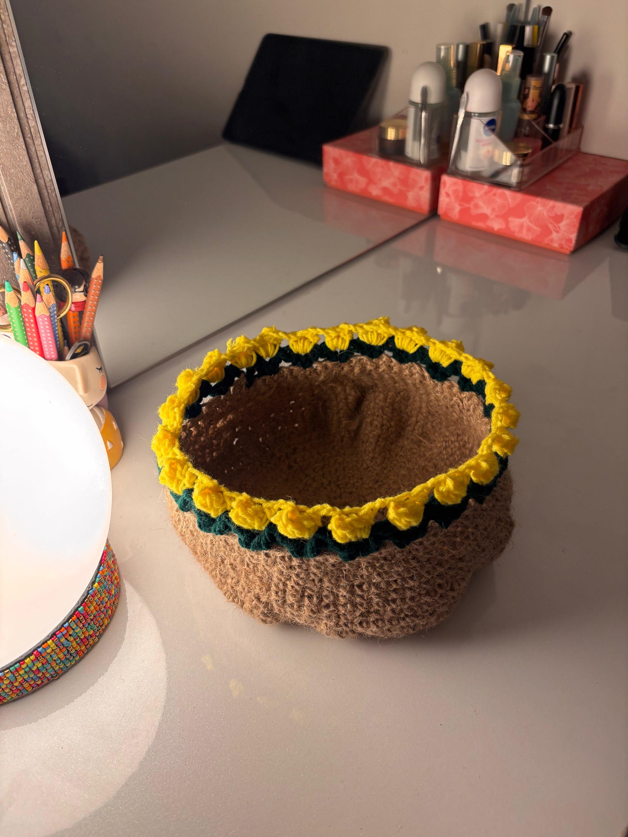 Knitted basket with yellow flower decorations on a desk