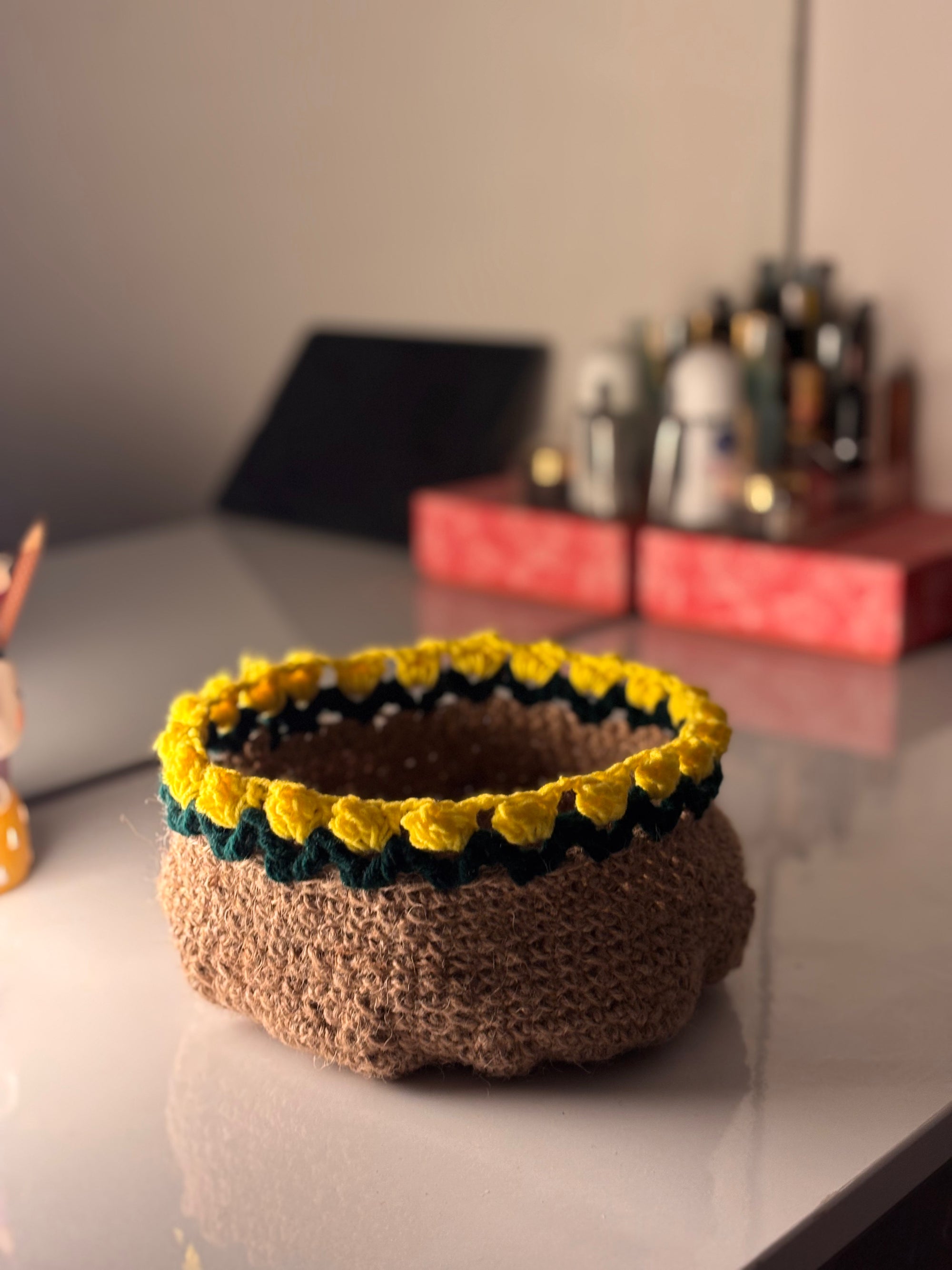 Knitted basket with yellow and green pattern on a reflective surface