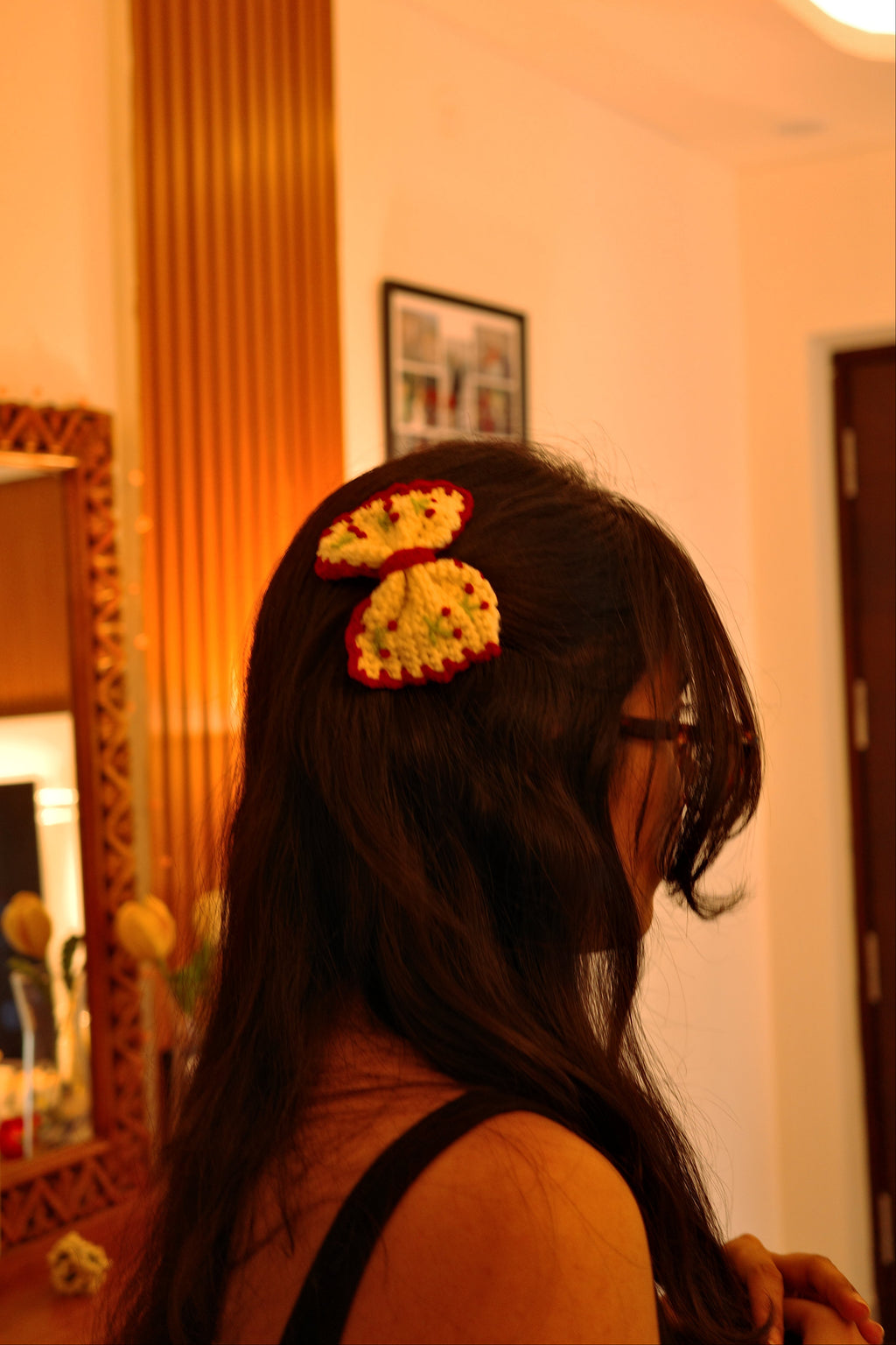 small handmade crochet cream bow with red border and tiny cherry details attached as a hair clip