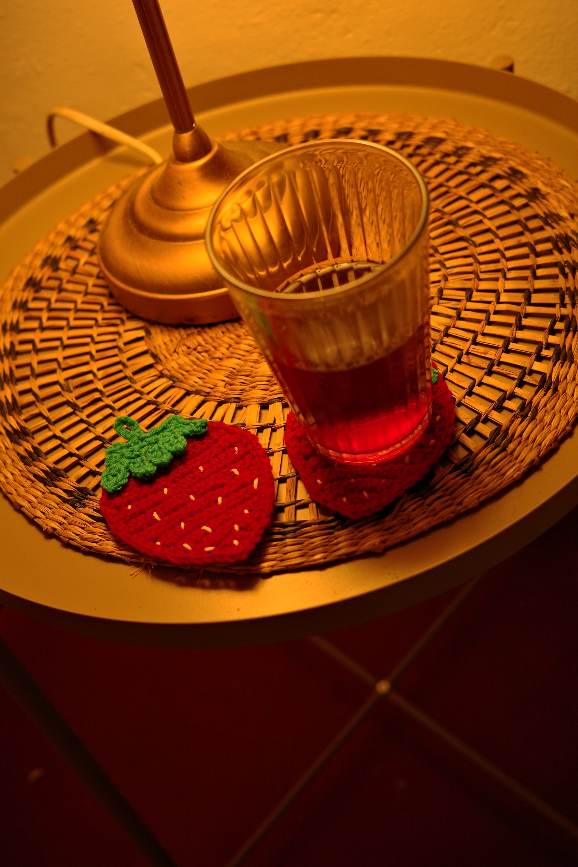 Wicker tablewith strawberry-shaped coasters and glass on a textured surface
