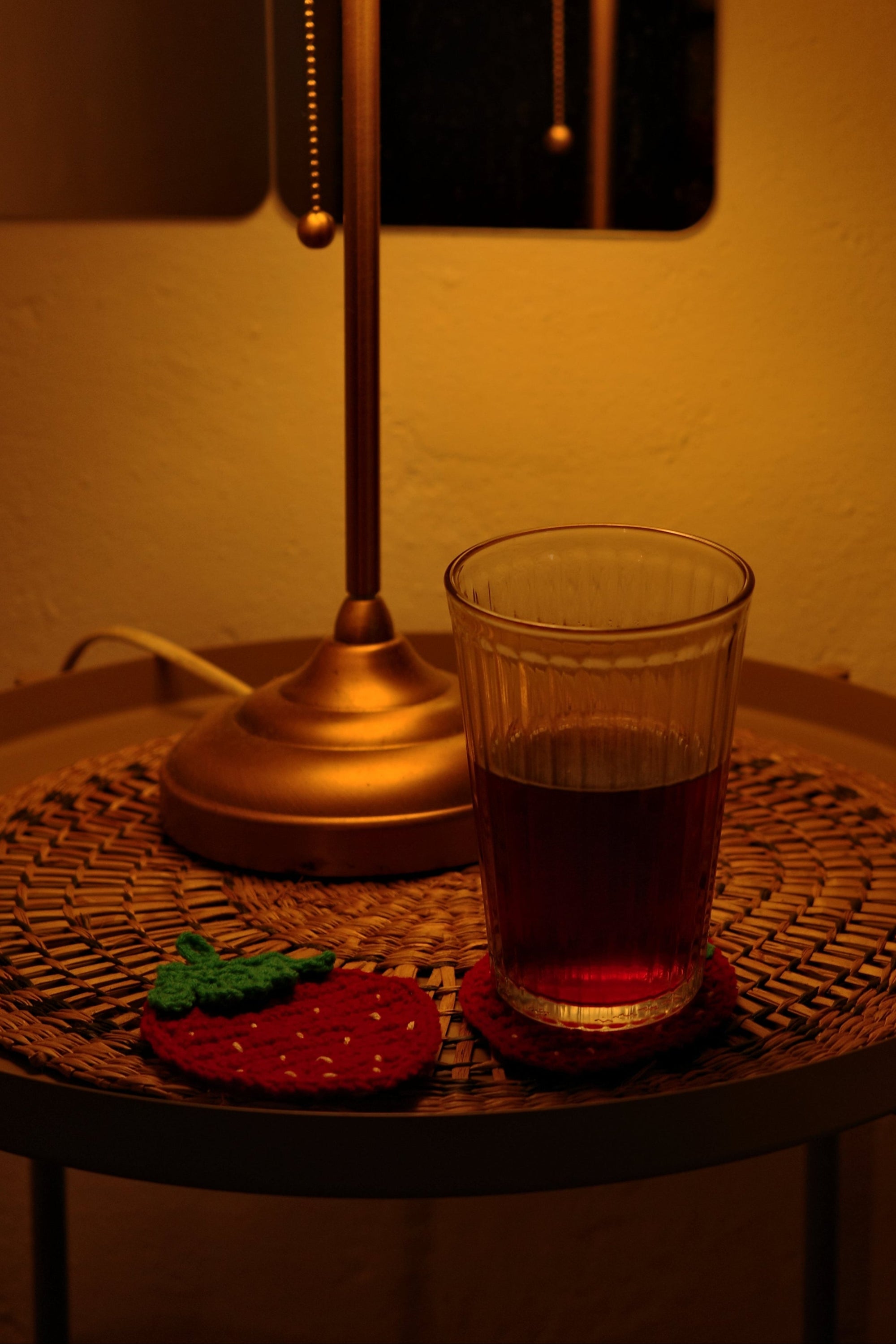Small round table with a lamp and glass on strabwerry crochet coasters