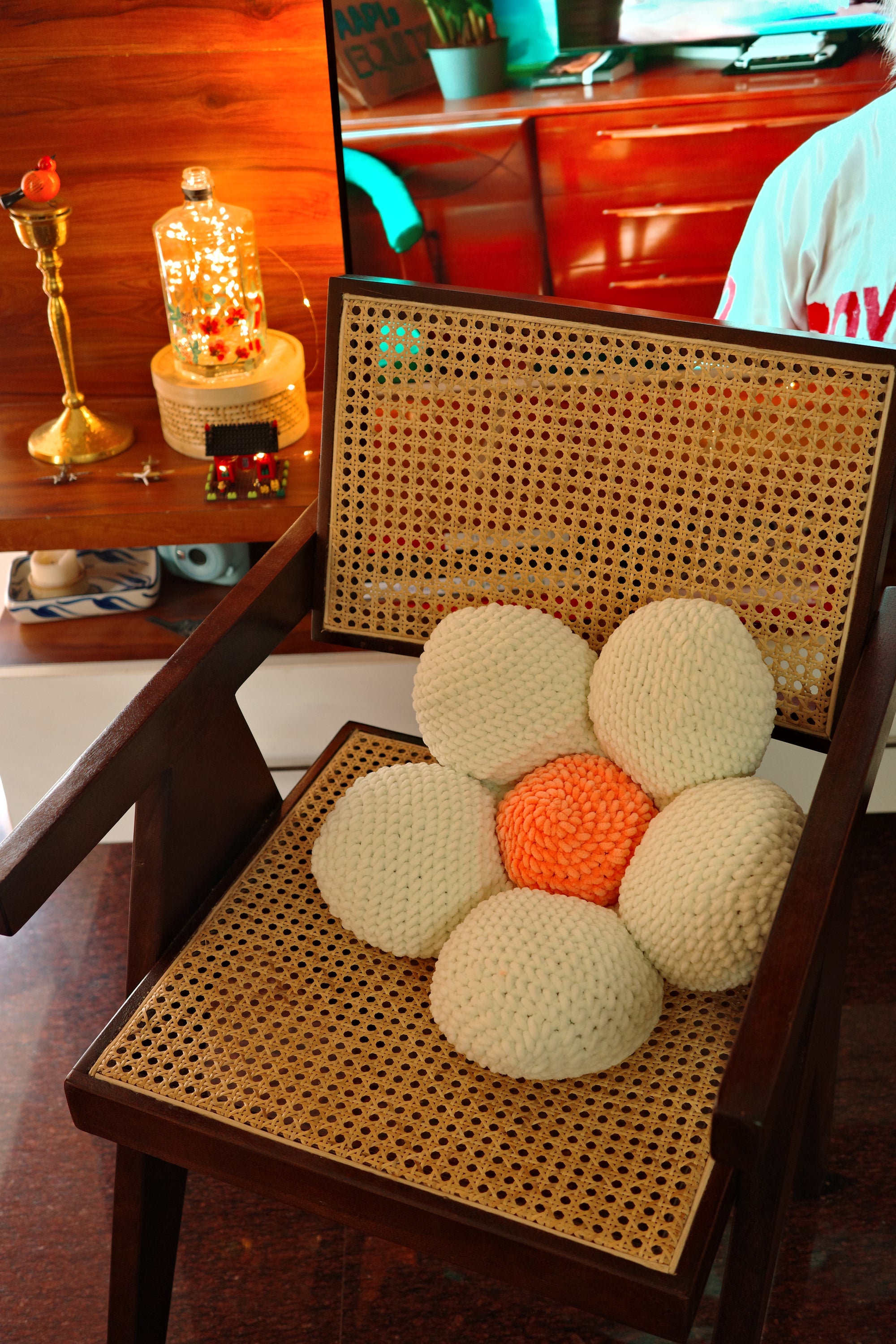 Decorative flower-shaped pillow on a wicker chair with a blurred background